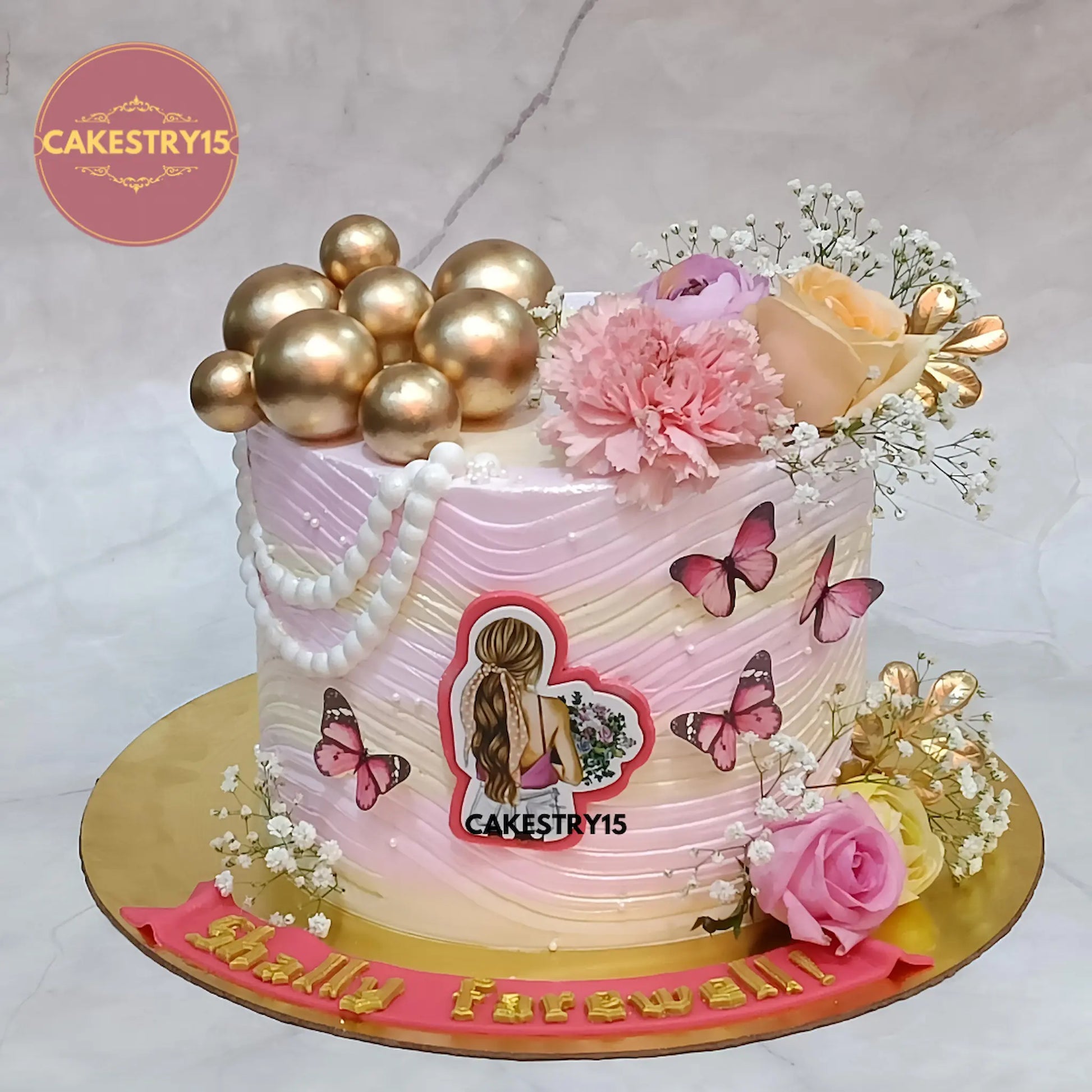 1kg butterscotch farewell cake with golden balls, roses, carnations, ferns, baby breath and butterflies from Cakestry15 Noida