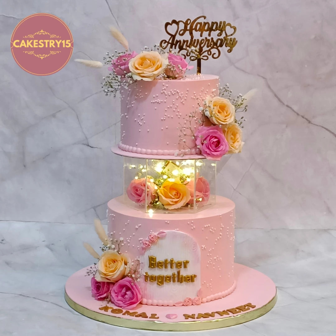 Premium eggless 25th anniversary cake with a hexagon spacer, fresh roses, lights, personalised names and elegant floral detailing, handcrafted for anniversary celebrations in Noida.