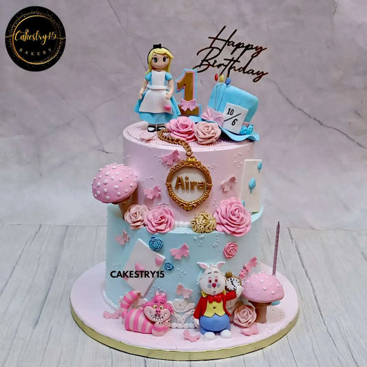 Alice in Wonderland-themed birthday cake for Aira’s 1st birthday featuring Alice, White Rabbit, Cheshire Cat, fondant roses, mushrooms, and a 10/6 hat.