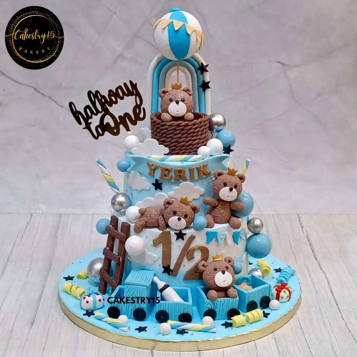Teddy-themed two-tier chocolate cake for a six-month birthday celebration with hot air balloon, rainbow, train, and teddies by cakestry15, noida bakery