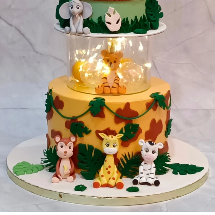 Animal Kingdom kids birthday cake featuring lion, monkey, elephant, giraffe, zebra, tiger and baby figurine, handcrafted as a theme cake Noida with premium eggless cakes.