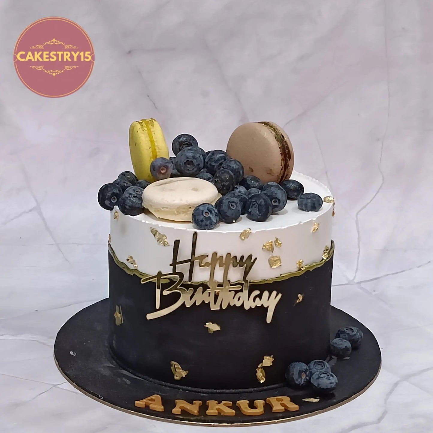 Elegant eggless boss birthday cake in chocolate flavour with ivory and black design, blueberries and macarons by Cakestry15 Noida