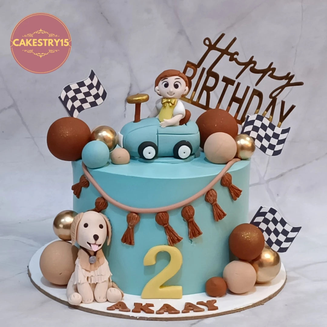 Eggless Car Theme Road Trip kids birthday cake in Noida featuring a kid figurine in a car, racing flags, faux balls, and a dog figurine for a memorable theme cake celebration.