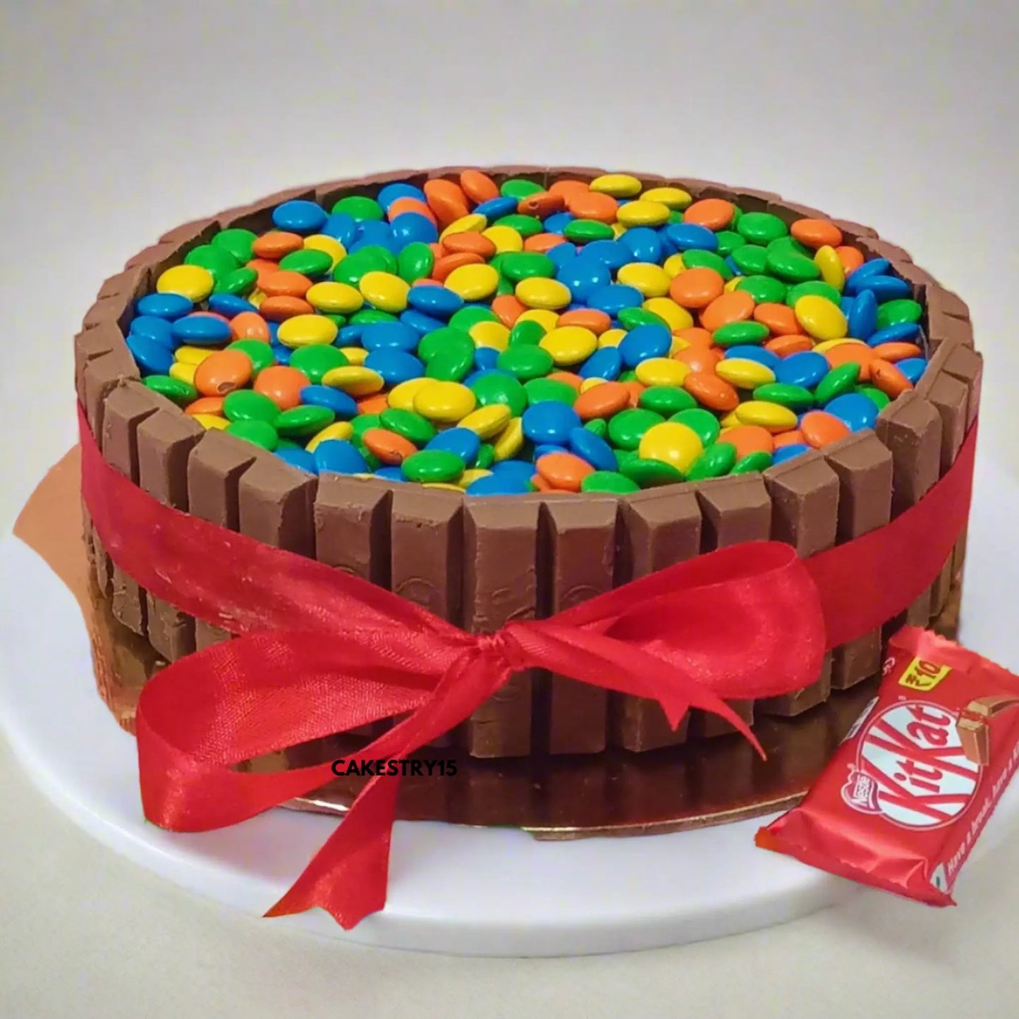 Chocolate KitKat cake layered with ganache, topped with gems, from Cakestry15 Noida