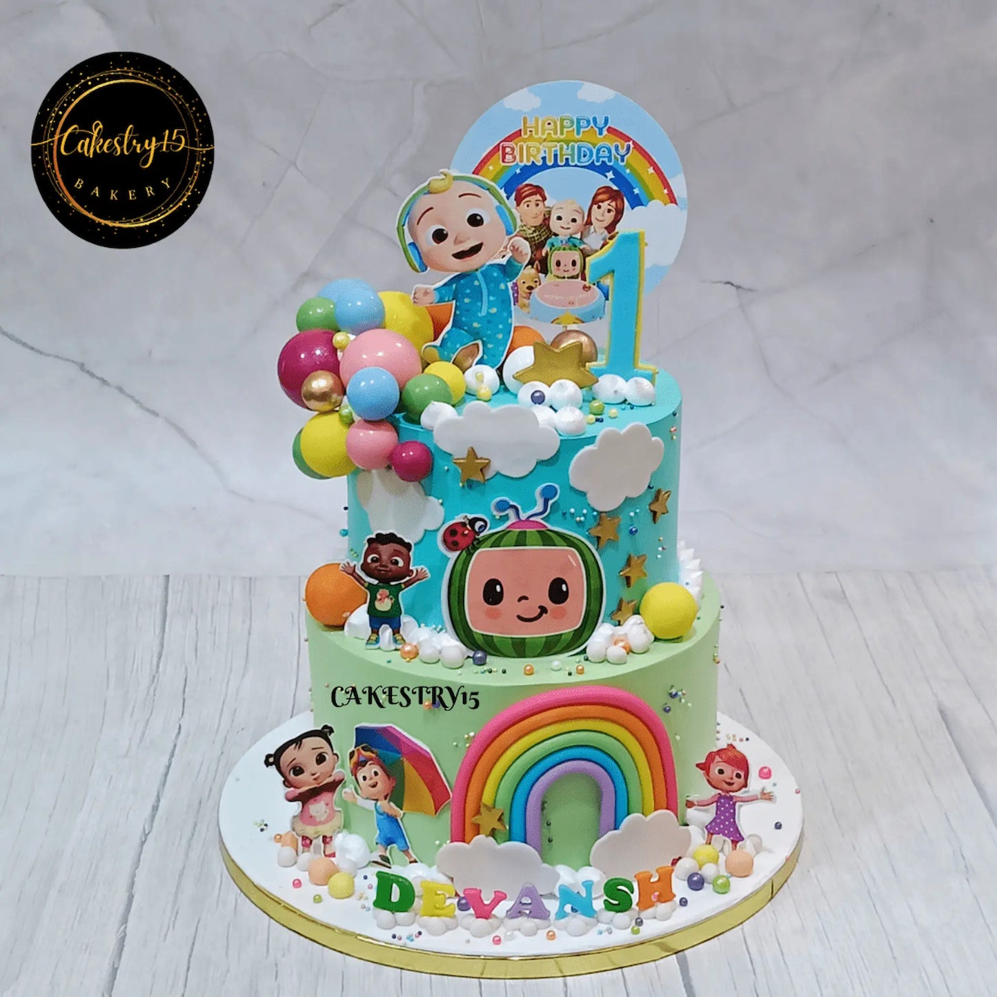 Eggless cocomelon first birthday cake in Noida with rainbow and colourful balls for kids birthday celebration