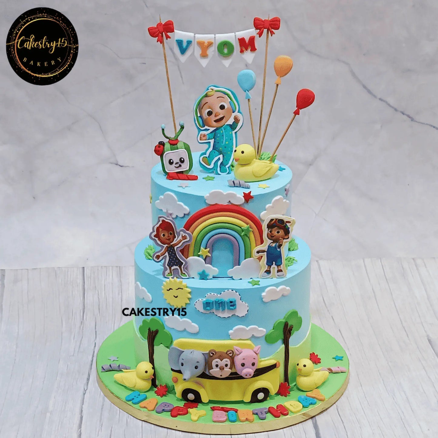 Cocomelon fun first birthday cake for Vyom eggless black forest two tier kids birthday cake in Noida with personalised name topper