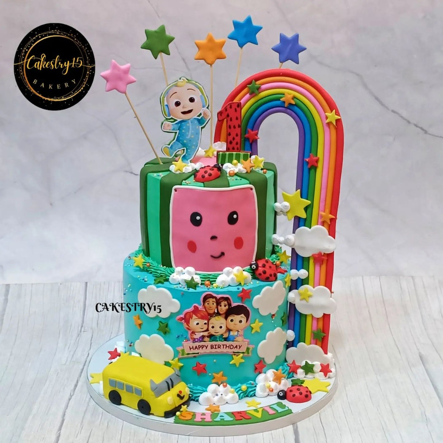 Eggless Cocomelon rainbow bus first birthday cake for kids in Noida with fondant characters and colourful theme design