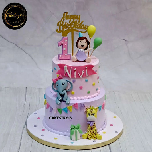 A 2-tier butterscotch-flavored safari theme cake for Nivi’s first birthday, featuring a girl figurine, fondant balloons, an elephant, and a giraffe by cakestry15 noida