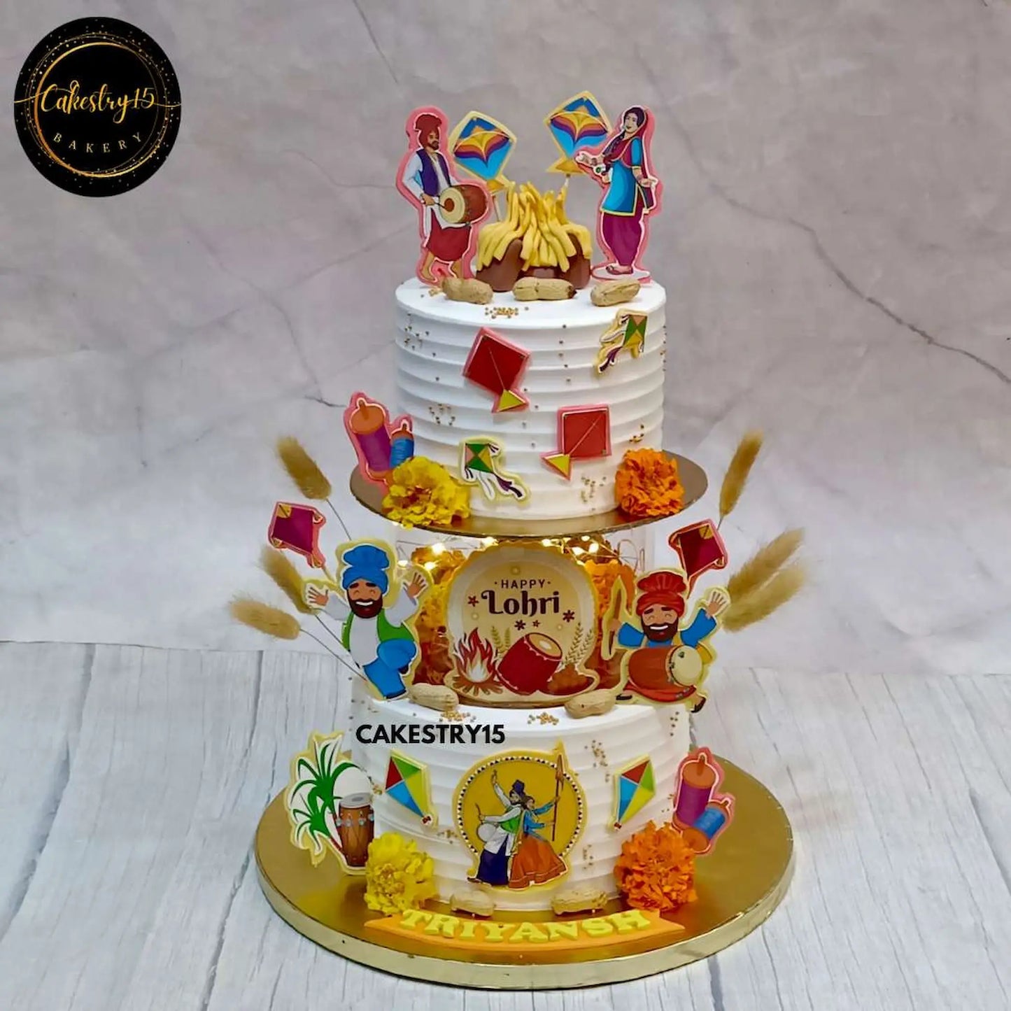 A 3kg butterscotch Lohri-themed cake with a lighted spacer, edible bonfire images, kites, dhol, and festive decorations by cakestry15 noida,festivals of india