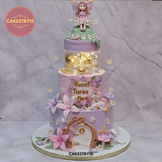 Hazel’s 5kg princess fairy theme chocolate butterscotch first birthday cake with rotating fairy figurine from Cakestry15 Noida