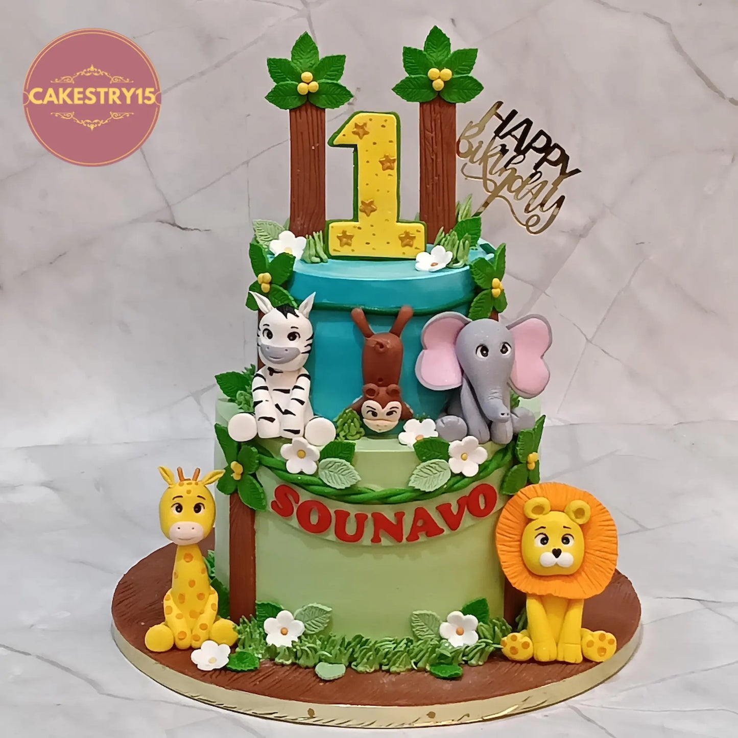 Jungle theme first birthday cake with fondant zebra, lion, elephant and giraffe in eggless truffle flavour for kids birthday in Noida
