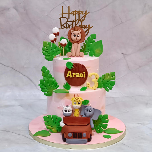 Jungle theme kids birthday cake with lion, zebra, giraffe and elephant seated in a jeep with fondant balloons and leaves.