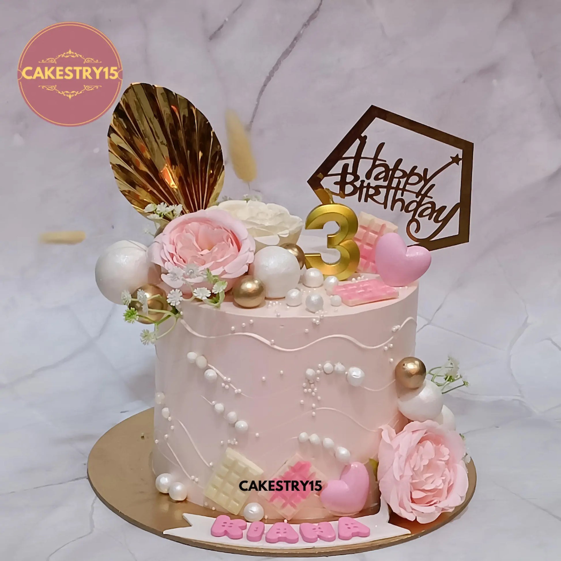 1kg pineapple birthday cake with floral theme, chocolate bars, pearls, topper, and candle from Cakestry15 Noida