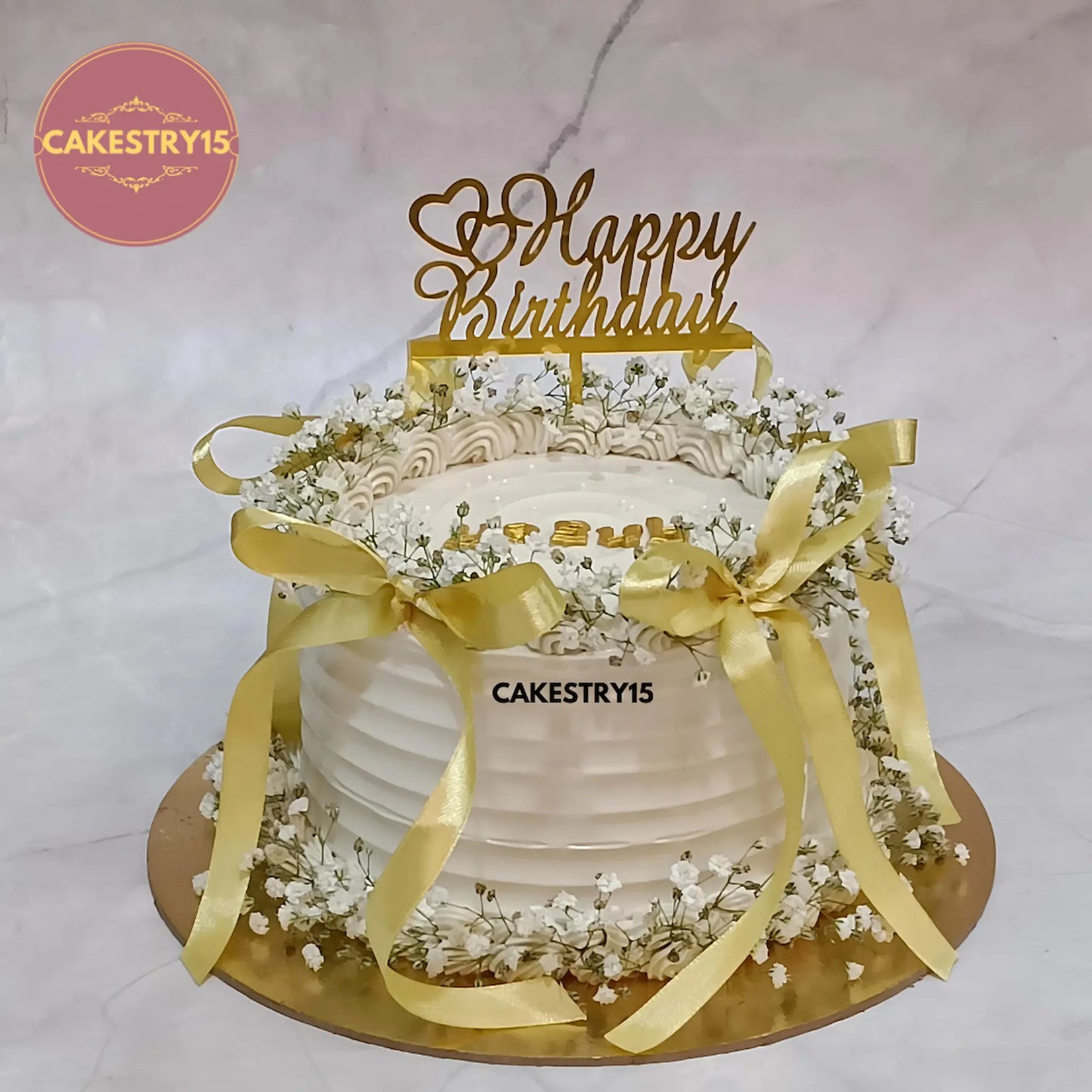 1kg eggless butterscotch birthday cake for wife topped with baby breath flowers and golden ribbon from Cakestry15 in Noida