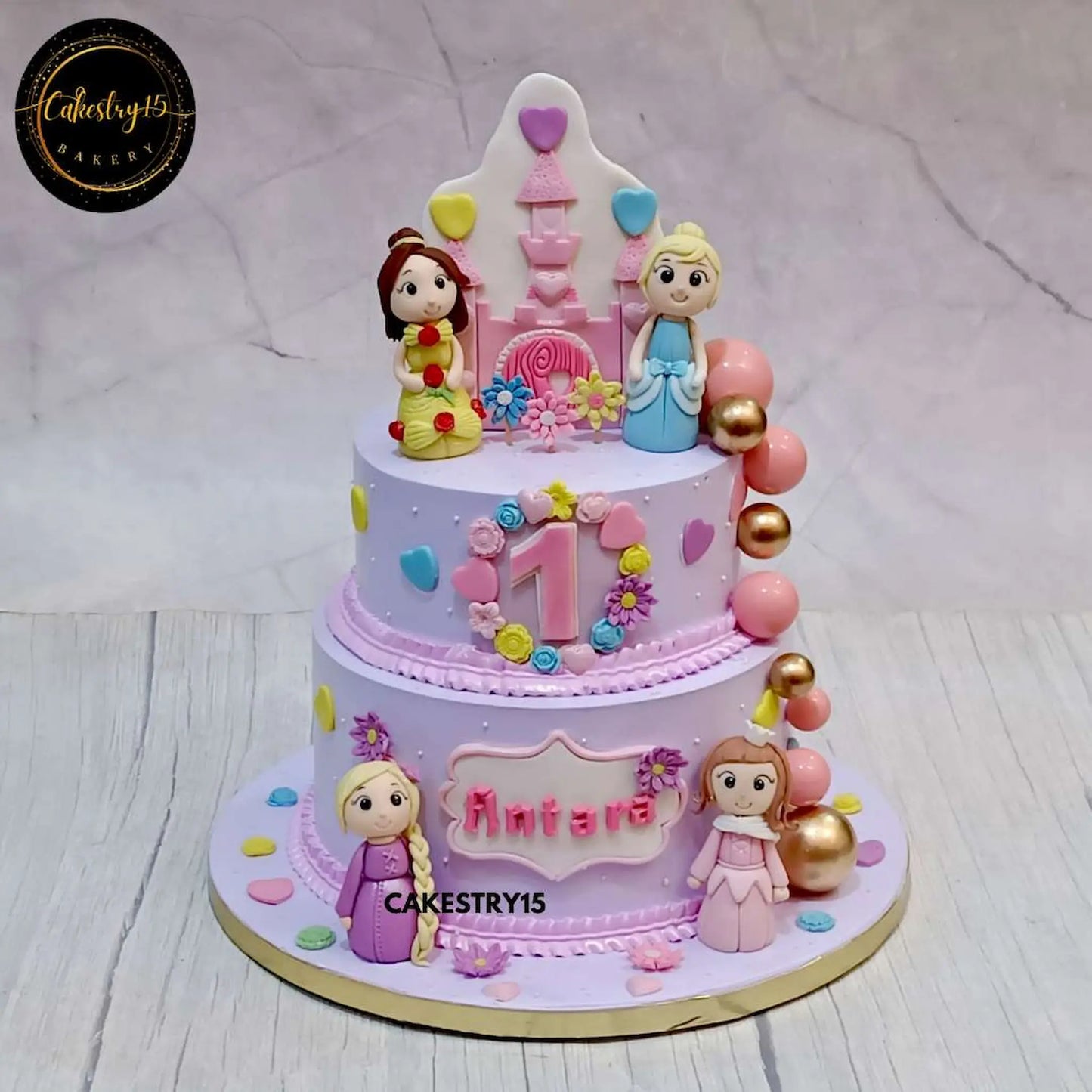 A two-tier blueberry princess-themed birthday cake featuring Rapunzel, Cinderella, Belle, and Aurora figurines with a castle on top, faux balls on one side, and flowers all over by cakestry15 noida