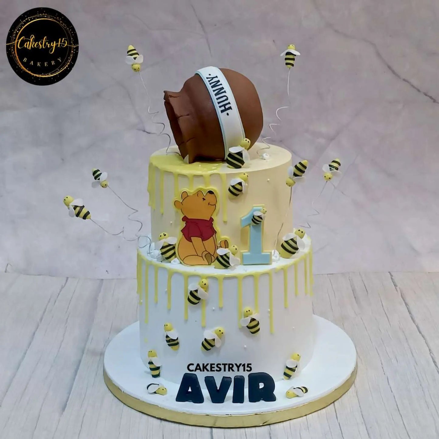 A 3kg, 2-tier pineapple-flavored Winnie the Pooh birthday cake with chocolate honey drips, honeybees, and a honey bowl on top by cakestry15 noida