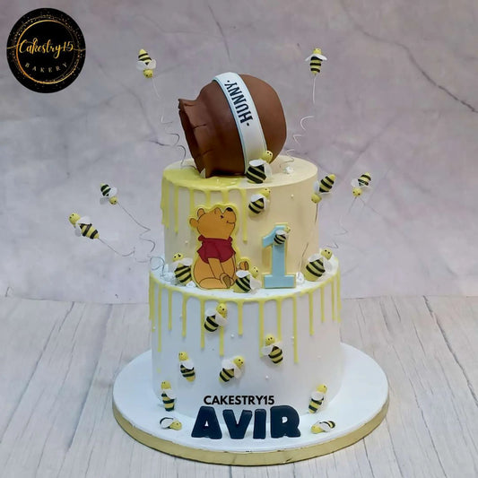 A 3kg, 2-tier pineapple-flavored Winnie the Pooh birthday cake with chocolate honey drips, honeybees, and a honey bowl on top by cakestry15 noida