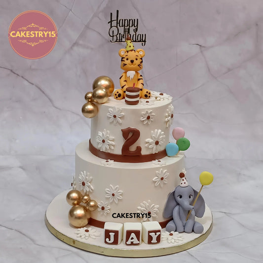 Two-tier butterscotch jungle theme cake with tiger, elephant, balloons, and fondant name by Cakestry15 Noida.