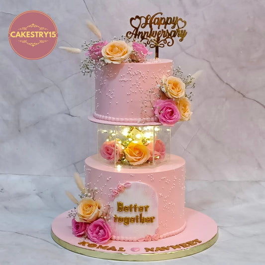 Premium eggless 25th anniversary cake with a hexagon spacer, fresh roses, lights, personalised names and elegant floral detailing, handcrafted for anniversary celebrations in Noida.