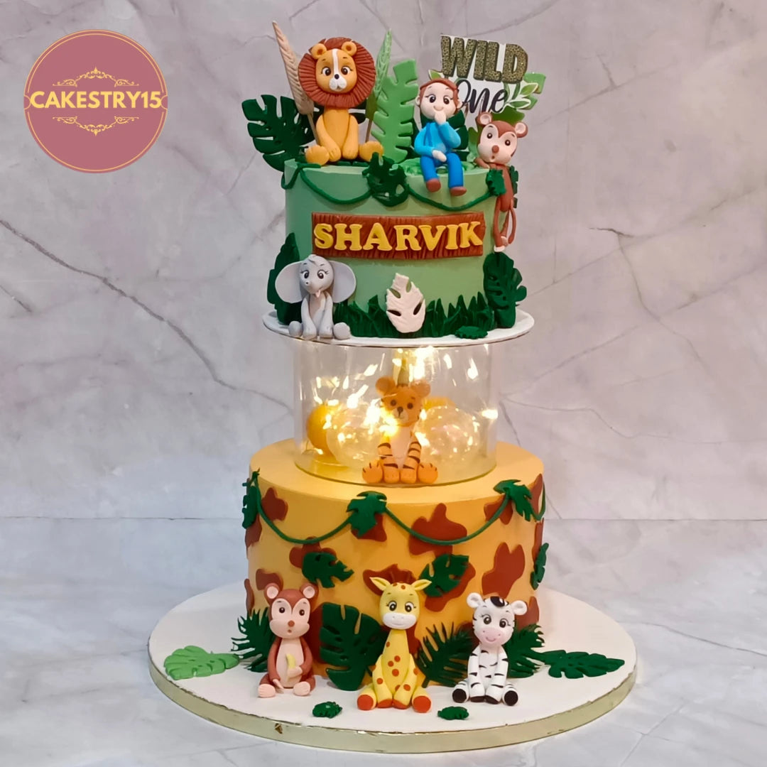 Animal Kingdom kids birthday cake featuring lion, monkey, elephant, giraffe, zebra, tiger and baby figurine, handcrafted as a theme cake Noida with premium eggless cakes.
