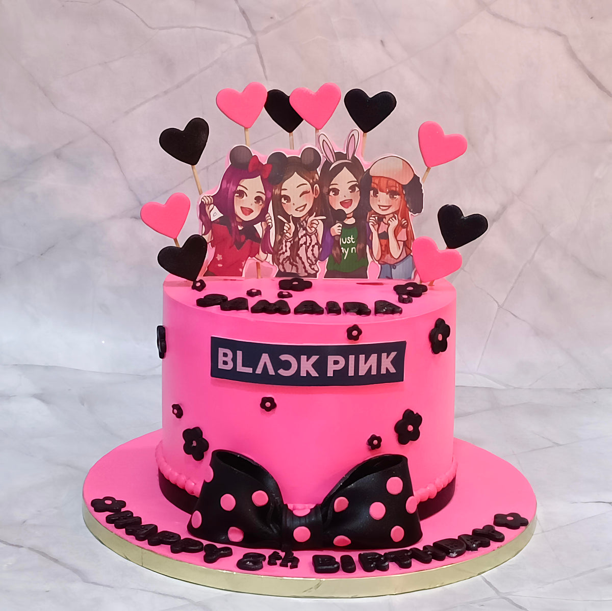 BLACKPINK Lisa birthday cake with pink frosting, character cutouts, and black and pink heart decorations.