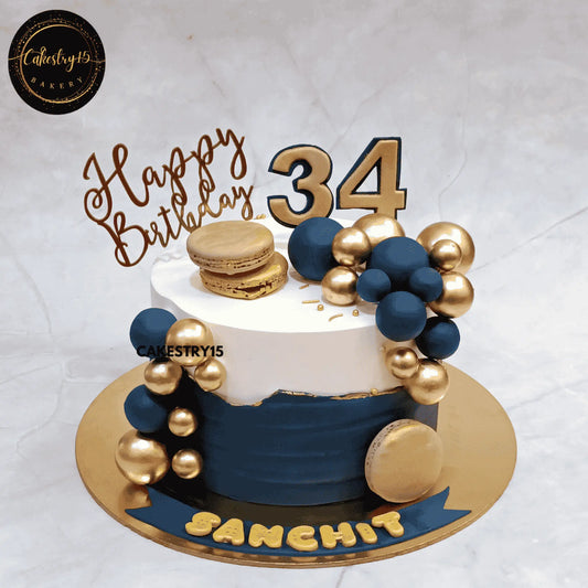 Elegant blue and ivory eggless birthday cake for men featuring macarons and decorative accents, available for cake delivery in Noida and Delhi NCR.