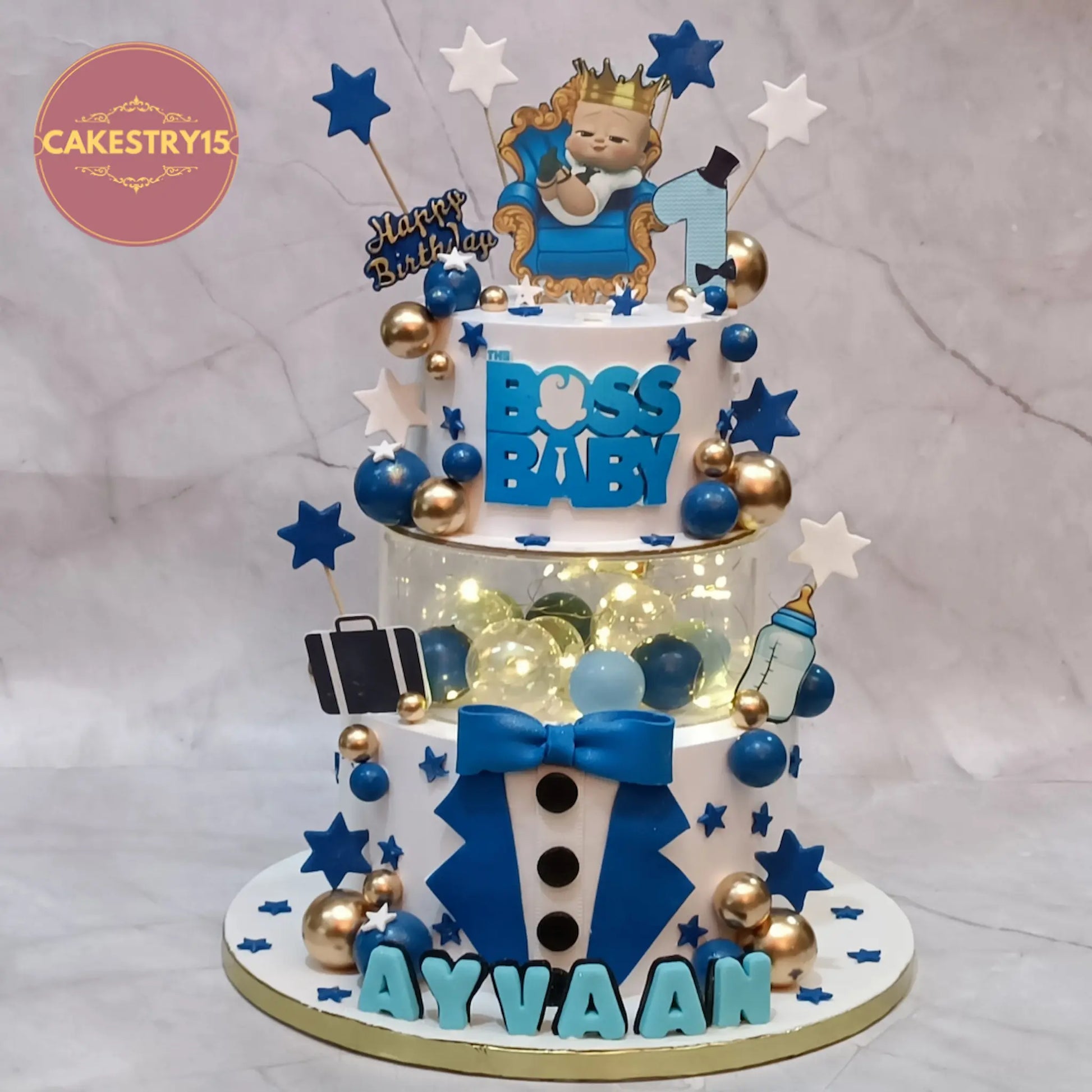 Boss Baby theme first birthday cake with tuxedo design, spacer with lights, logo, and edible elements in eggless choco vanilla by Cakestry15 Noida
