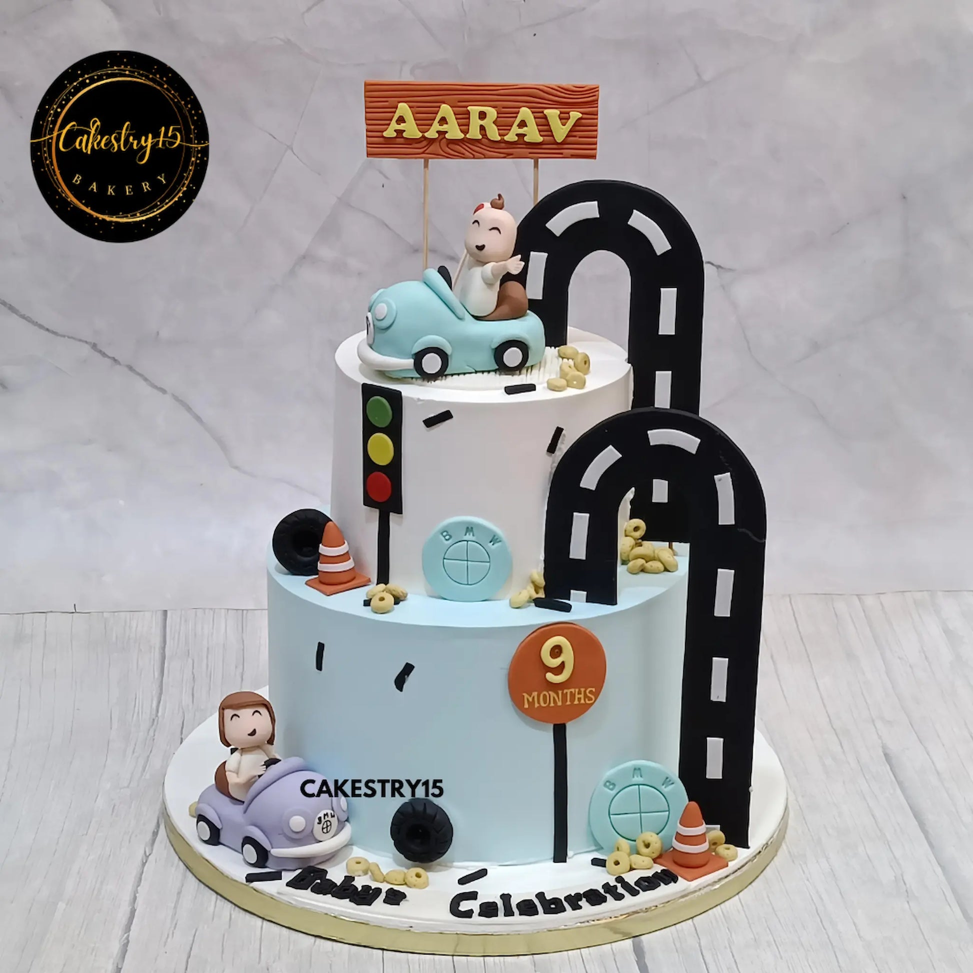 Car theme eggless black forest baby cake with fondant cars and road design for a 9-month celebration in Noida by Cakestry15.
