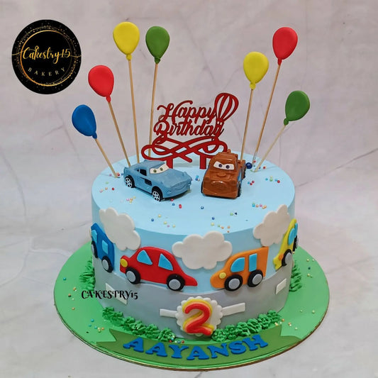 Car theme road adventure birthday cake in eggless blueberry flavour with toy cars and balloons for a kids birthday celebration in Noida