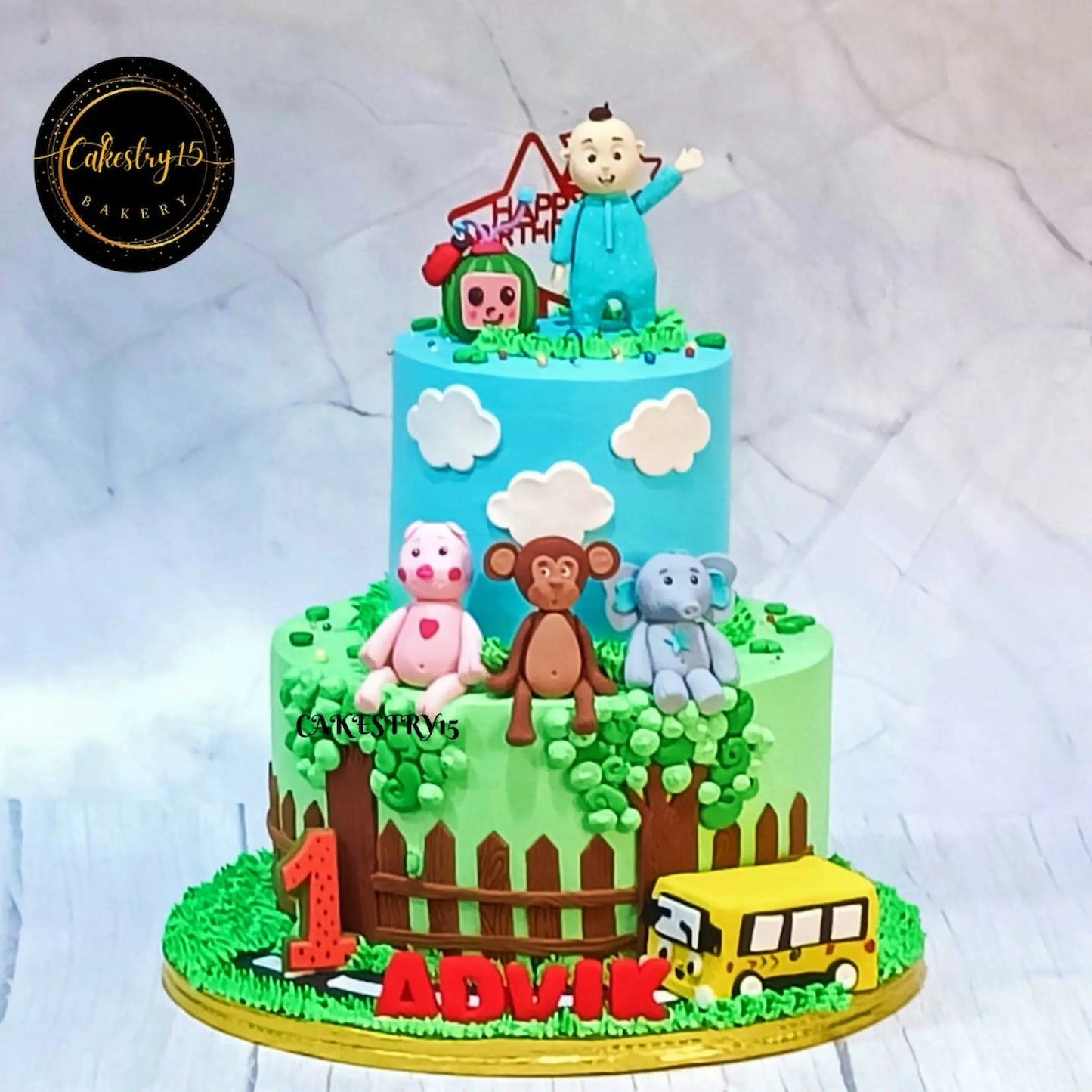 Cocomelon family first birthday cake 4kg eggless black forest theme cake Noida with bus TV and animal fondant design for kids celebration