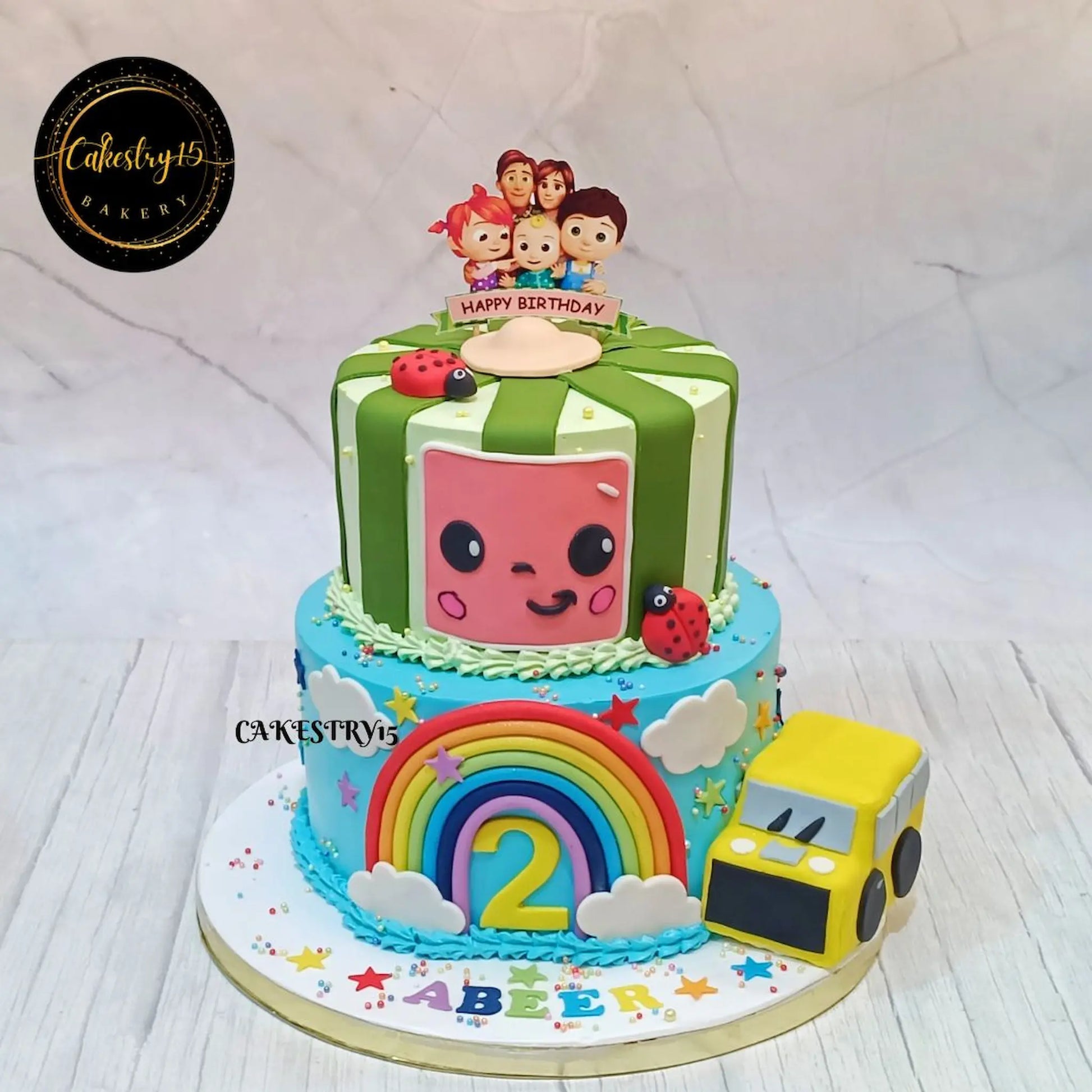 Eggless cocomelon family party kids birthday cake in Noida with rainbow bus fondant design chocolate flavour custom cake for kids