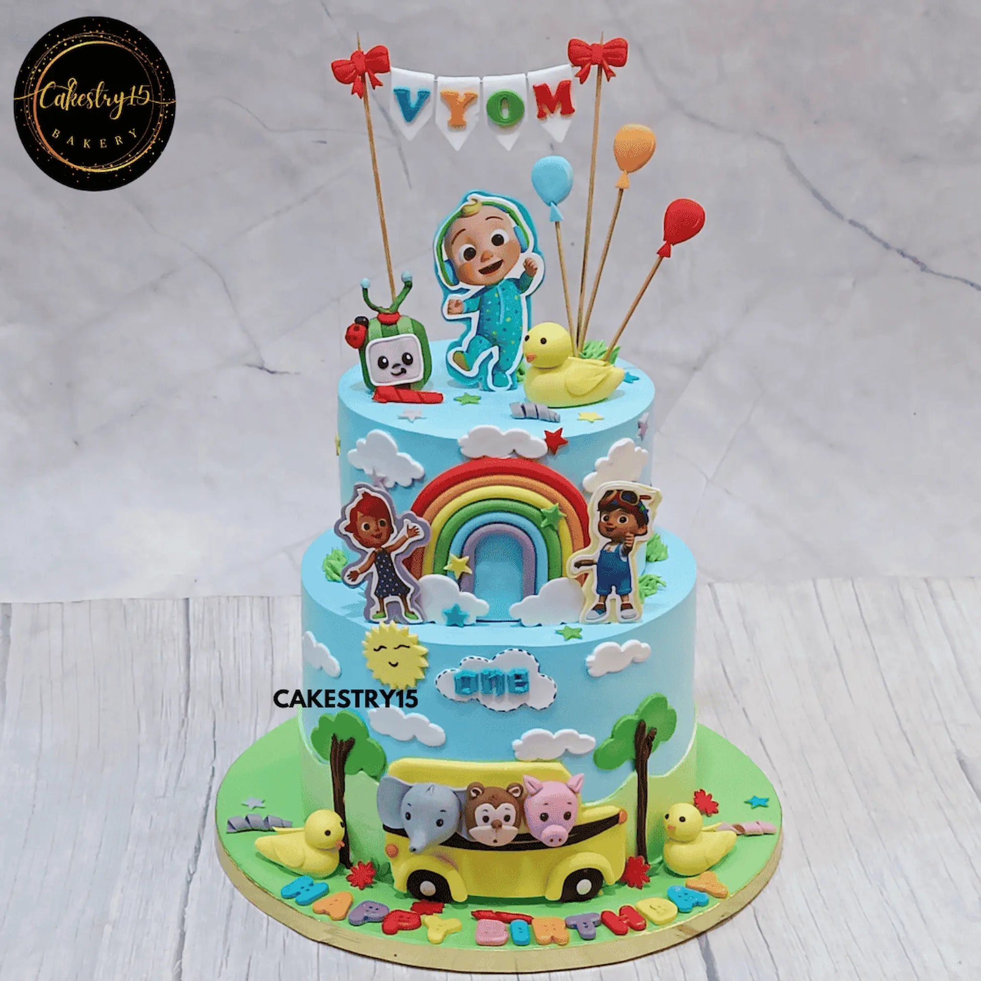 Cocomelon fun first birthday cake for Vyom eggless black forest two tier kids birthday cake in Noida with personalised name topper