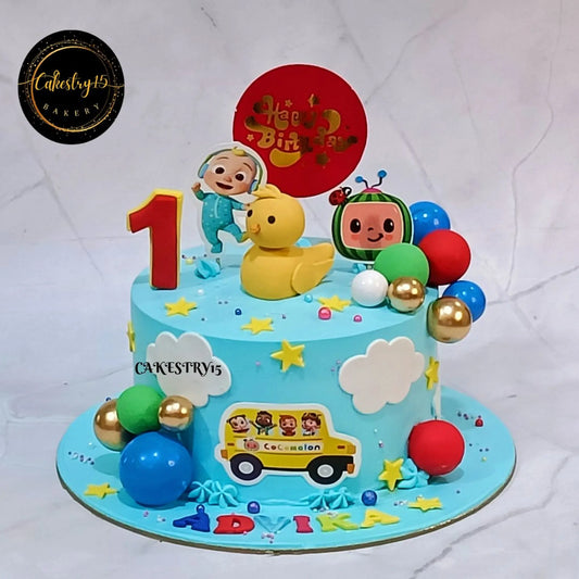 Cocomelon happy first birthday cake for kids with blueberry flavour, eggless theme cake in Noida with colorful toppers and custom name design