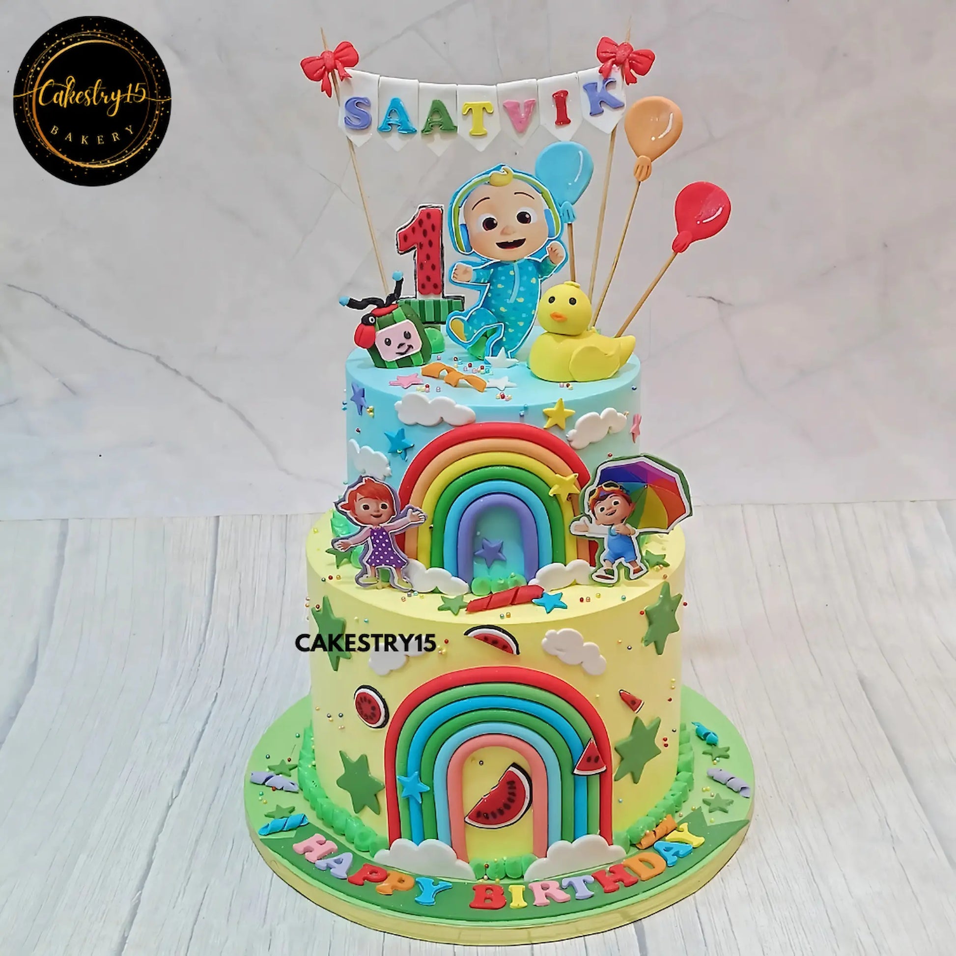 Eggless cocomelon theme first birthday cake with rainbow two tier design for kids in Noida by Cakestry15