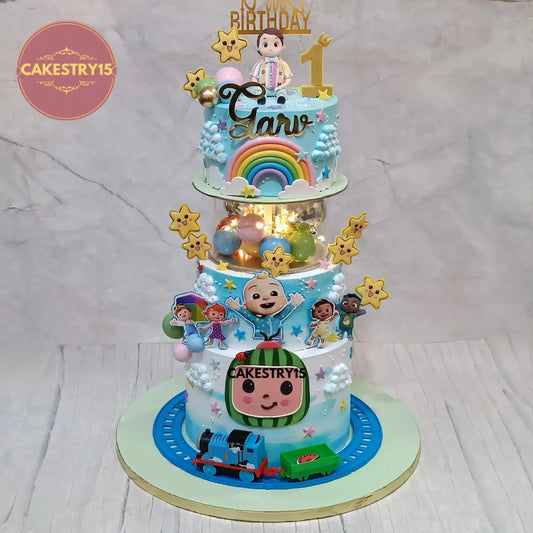 Eggless cocomelon theme first birthday cake with 3 tier chocolate design, toy train, fondant boy topper and custom kids cake in Noida
