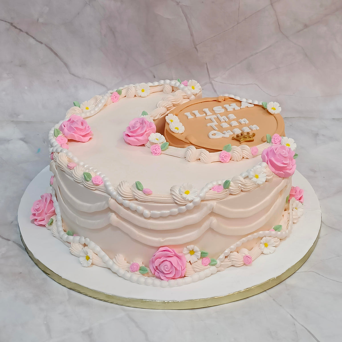 Side angle of a crescent theme kids birthday cake with ivory icing, fondant flowers and cream piping from an eggless cakes bakery in Noida.