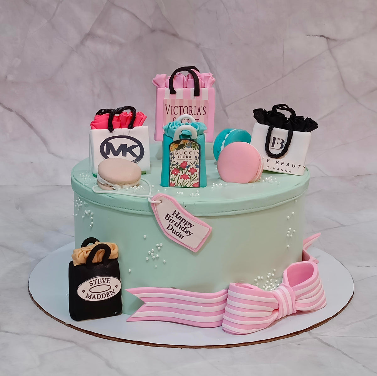 Elegant women's birthday theme cake Noida featuring a teal box design with handbags, perfume, macarons and eggless cakes craftsmanship.