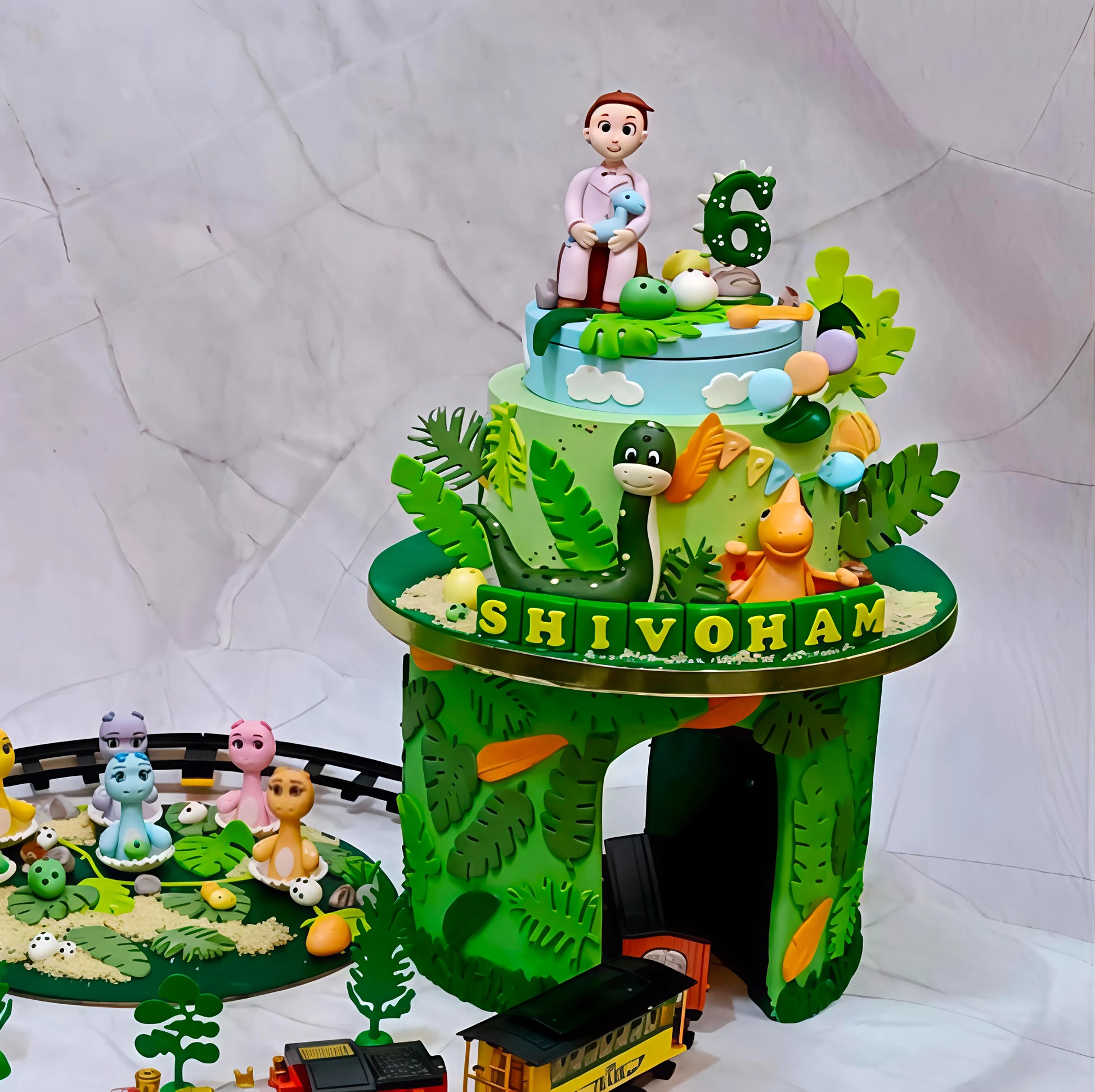 Dino theme cake tower featuring a train passing through the hollow lower section, designed as an eggless kids birthday cake in Noida.