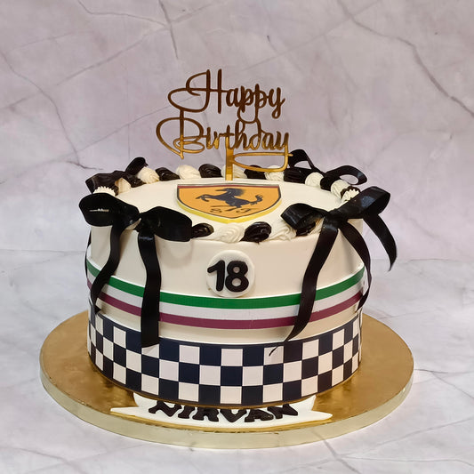 Ferrari theme 18th birthday chocolate cake with white ganache icing, Ferrari logo, racing track detailing and a satin black bow.