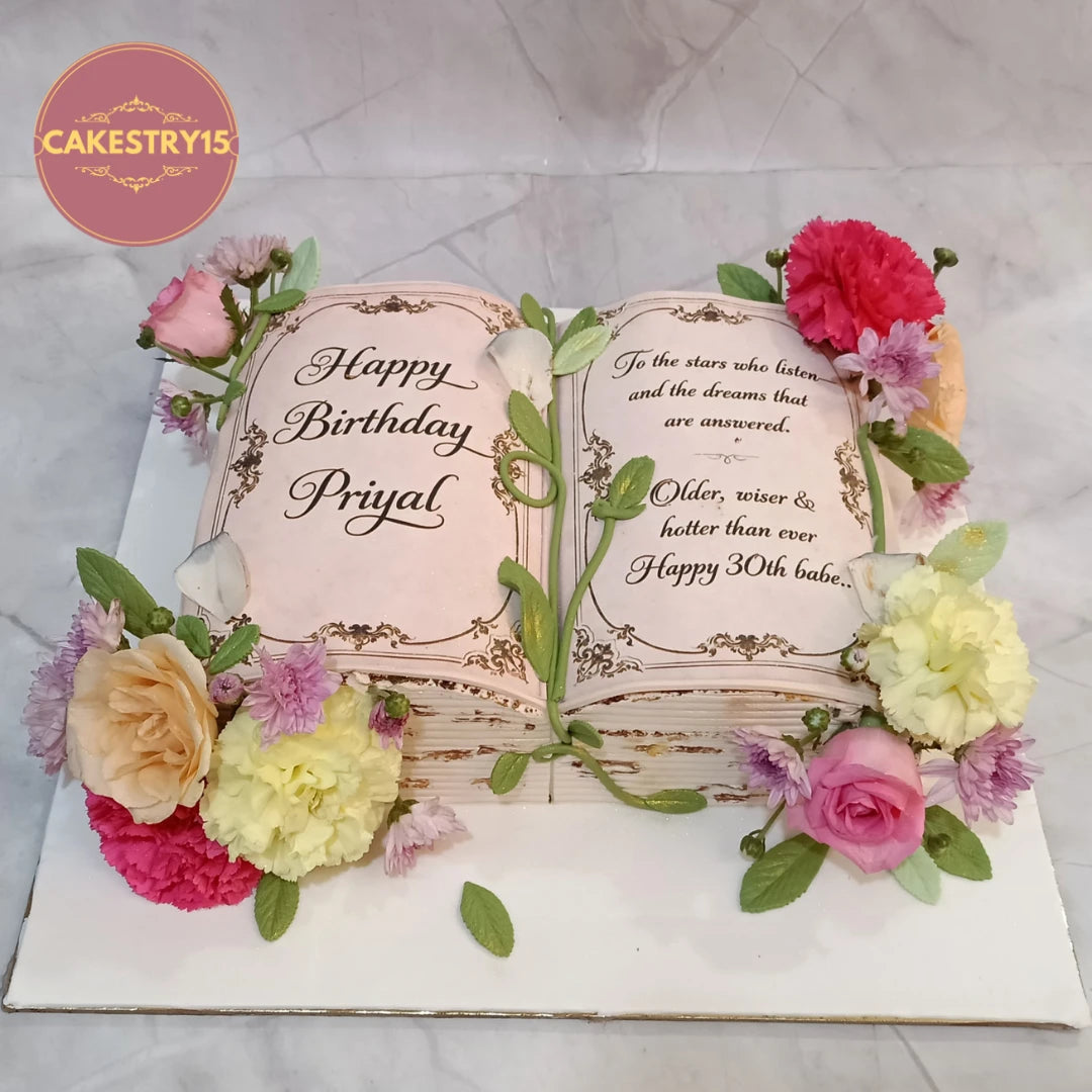 Floral book theme birthday cake with custom messages and fresh flowers, a premium theme cake Noida design from Cakestry15 featuring eggless cakes for special celebrations.