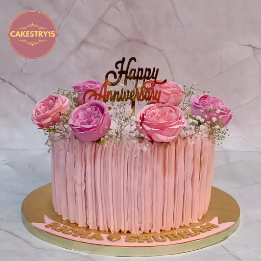 Elegant eggless anniversary cake with pink roses and gold topper, handcrafted as a designer theme cake Noida using premium eggless cakes.