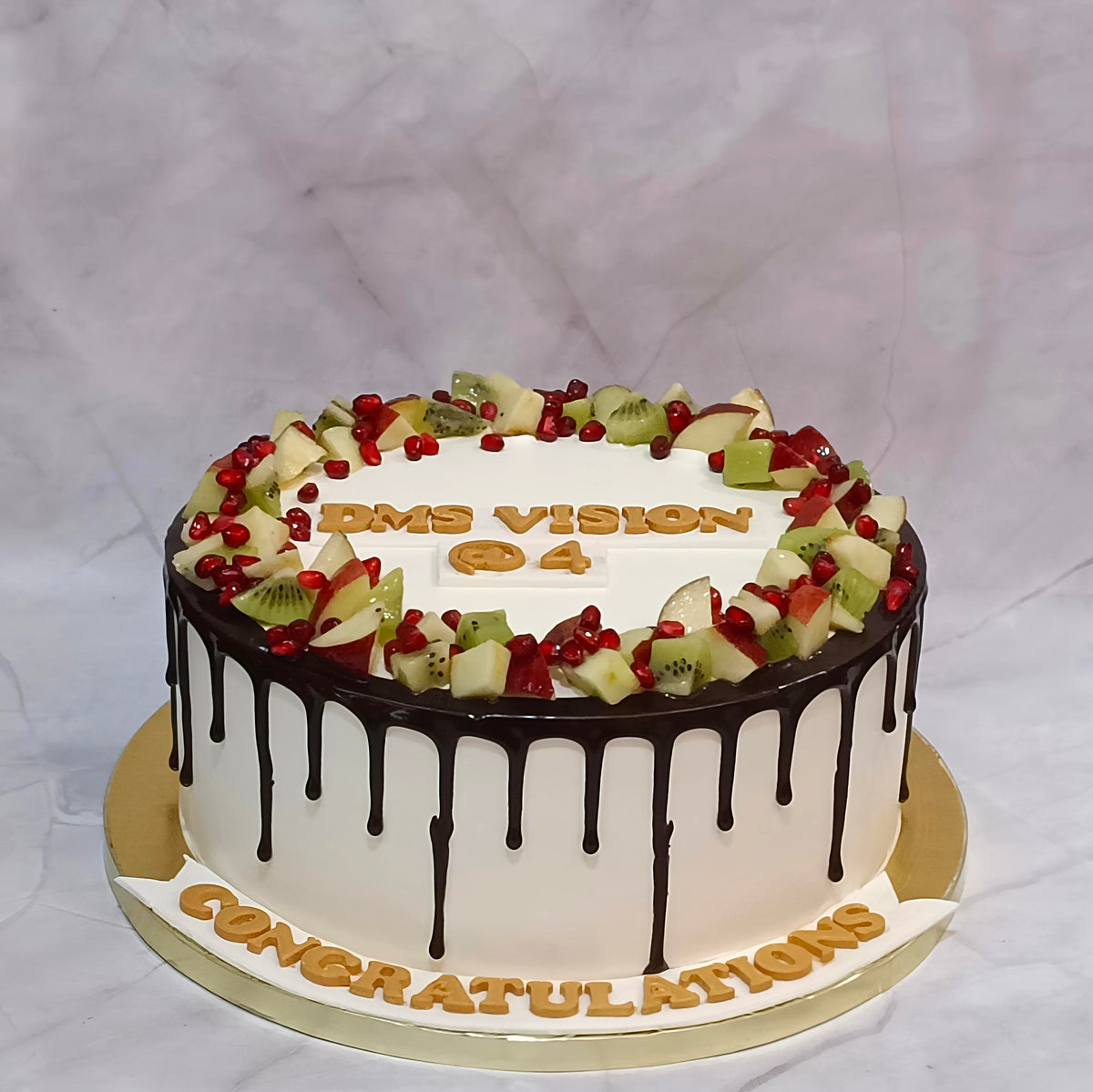 Premium eggless fresh fruit chocolate drip cake topped with apples, kiwis and pomegranates, perfect for birthdays, anniversaries, corporate celebrations and gifting in Noida.