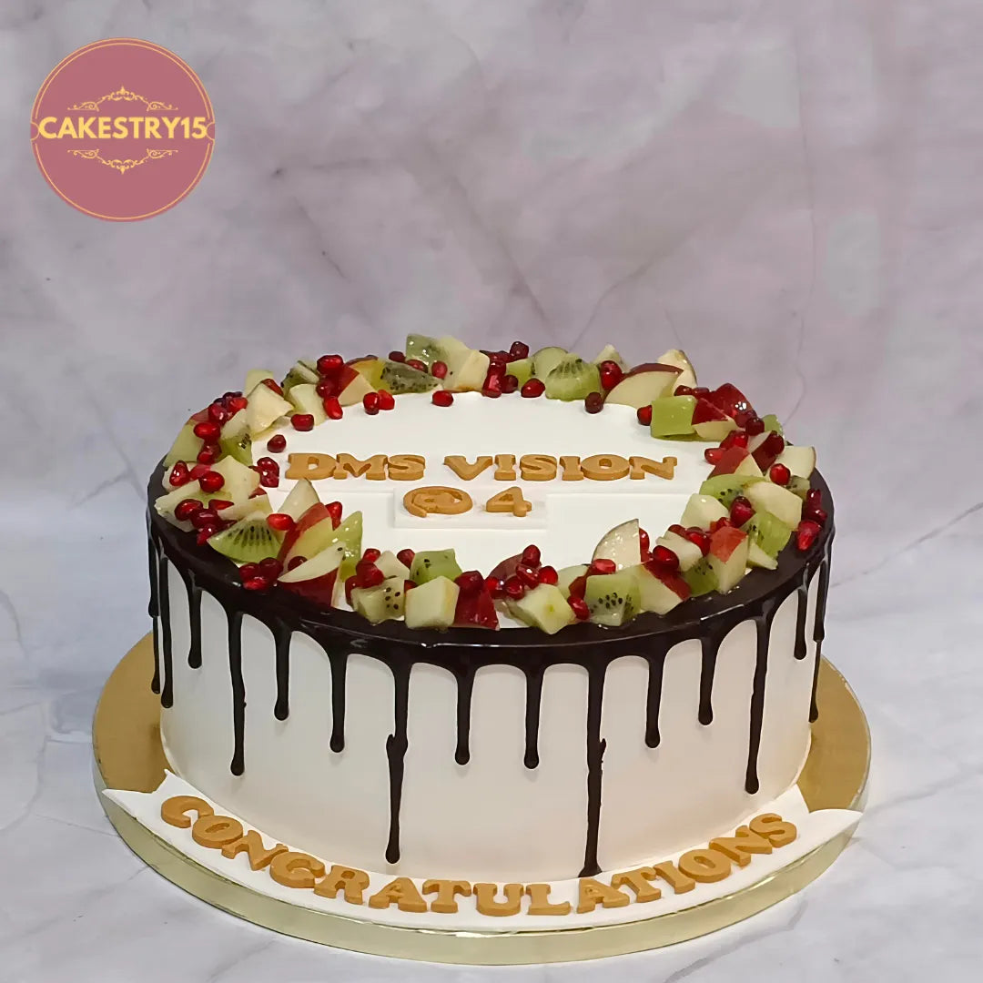Premium eggless fresh fruit chocolate drip cake topped with apples, kiwis and pomegranates, perfect for birthdays, anniversaries, corporate celebrations and gifting in Noida.