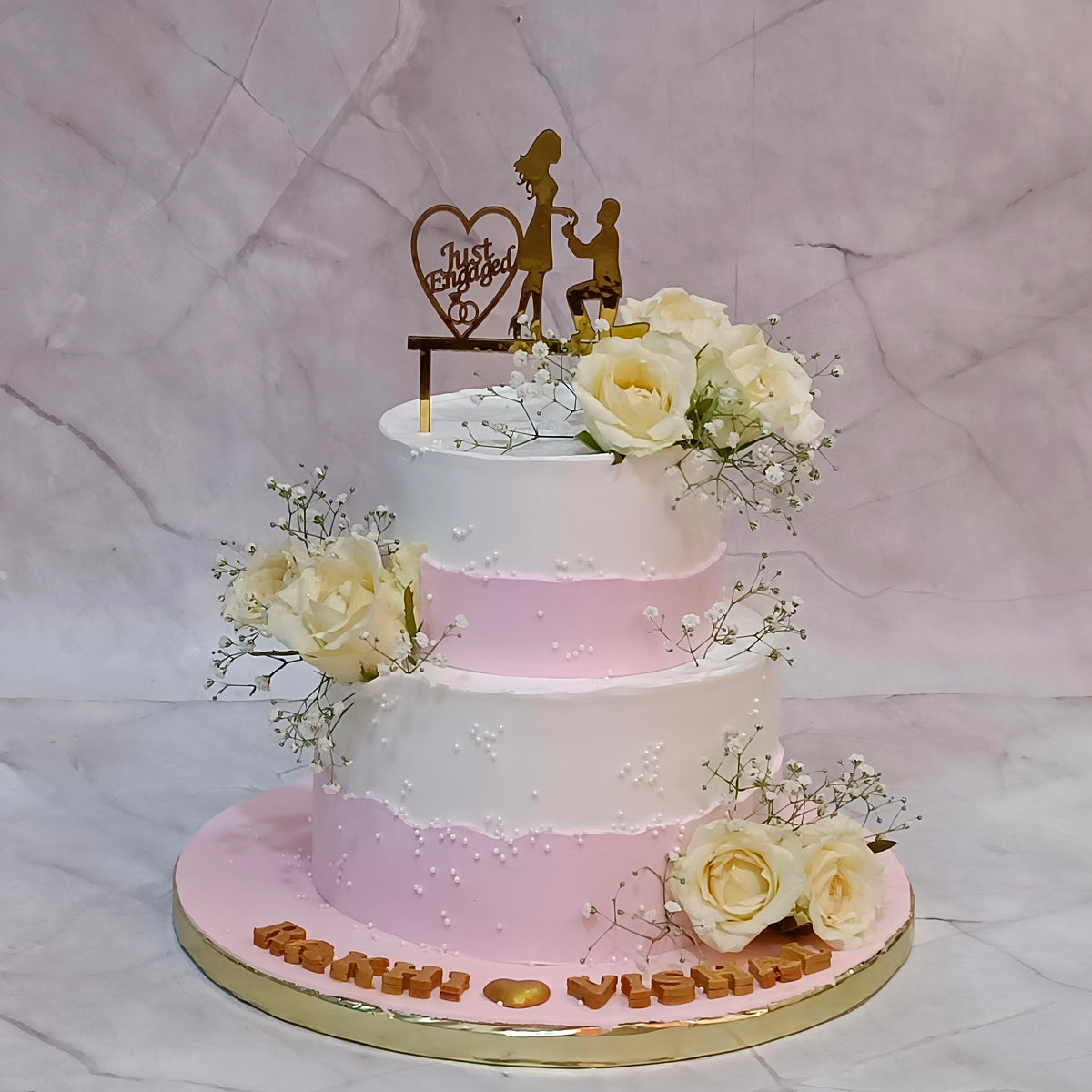 Two-tier Just Engaged theme cake topped with fresh roses and baby's breath.