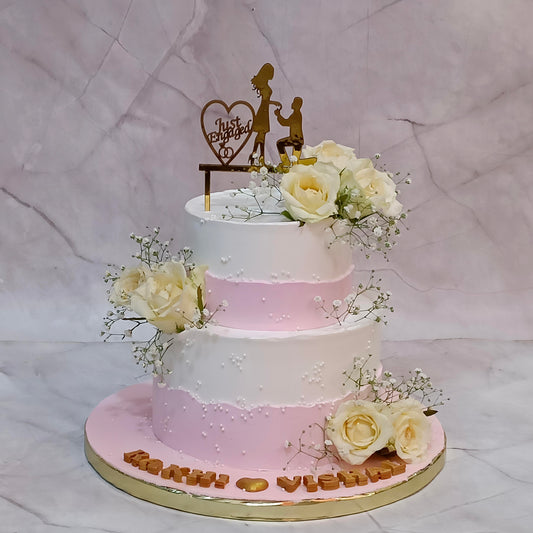Two-tier Just Engaged theme cake topped with fresh roses and baby's breath.