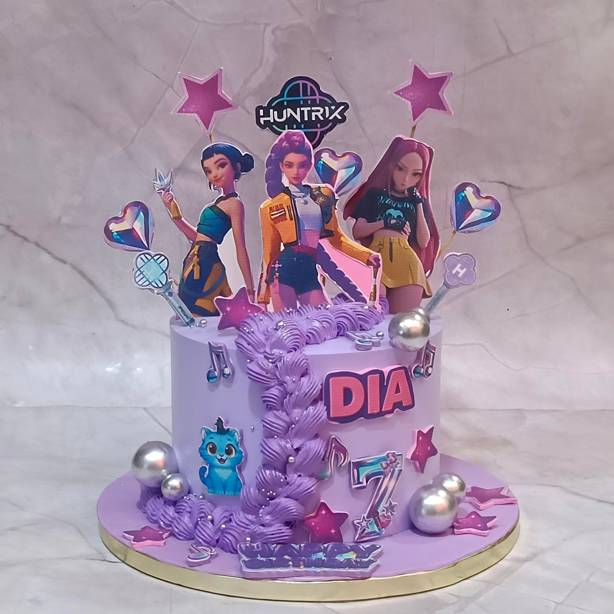 K-Pop Huntrix birthday cake with edible images of three K-pop girls, hearts, stars and faux silver balls.