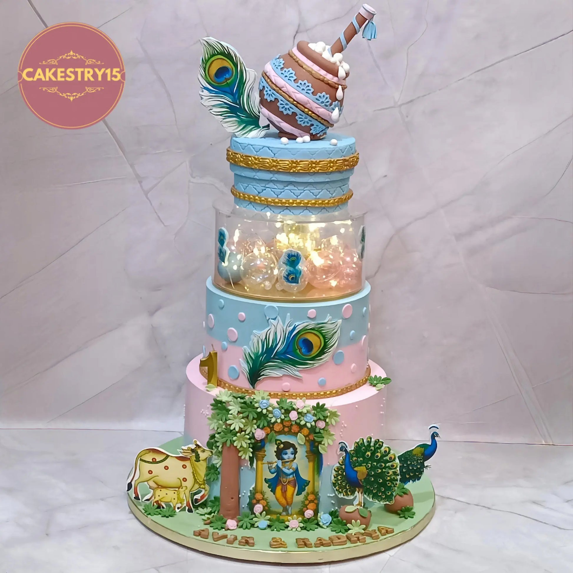 Eggless Krishna twins birthday cake with rotating dahi handi, premium theme cake Noida for first birthday celebrations.
