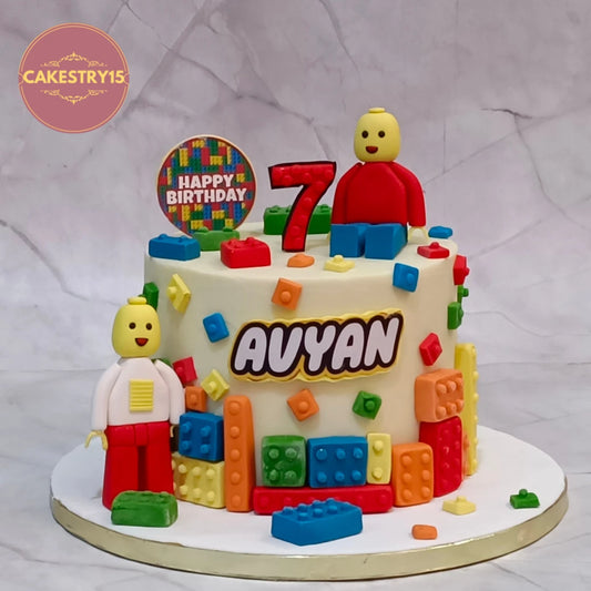 Eggless Lego kids birthday cake for Avyan with ivory icing, colourful toy brick decorations, two Lego minifigures and a red number 7 topper, a premium theme cake in Noida.