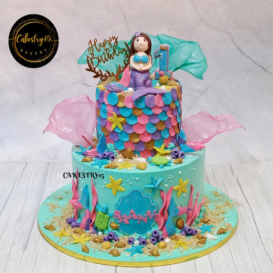 Mermaid Princess Ocean theme kids birthday cake with a fondant mermaid, waves and coral elements from an eggless cakes bakery offering a theme cake Noida.