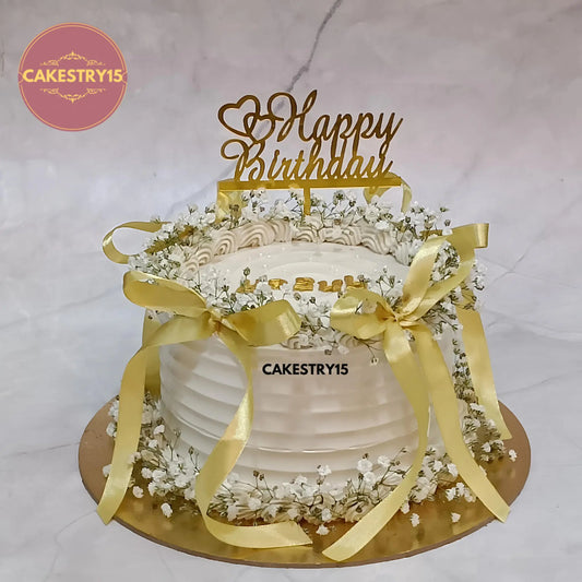 1kg eggless butterscotch birthday cake for wife topped with baby breath flowers and golden ribbon from Cakestry15 in Noida
